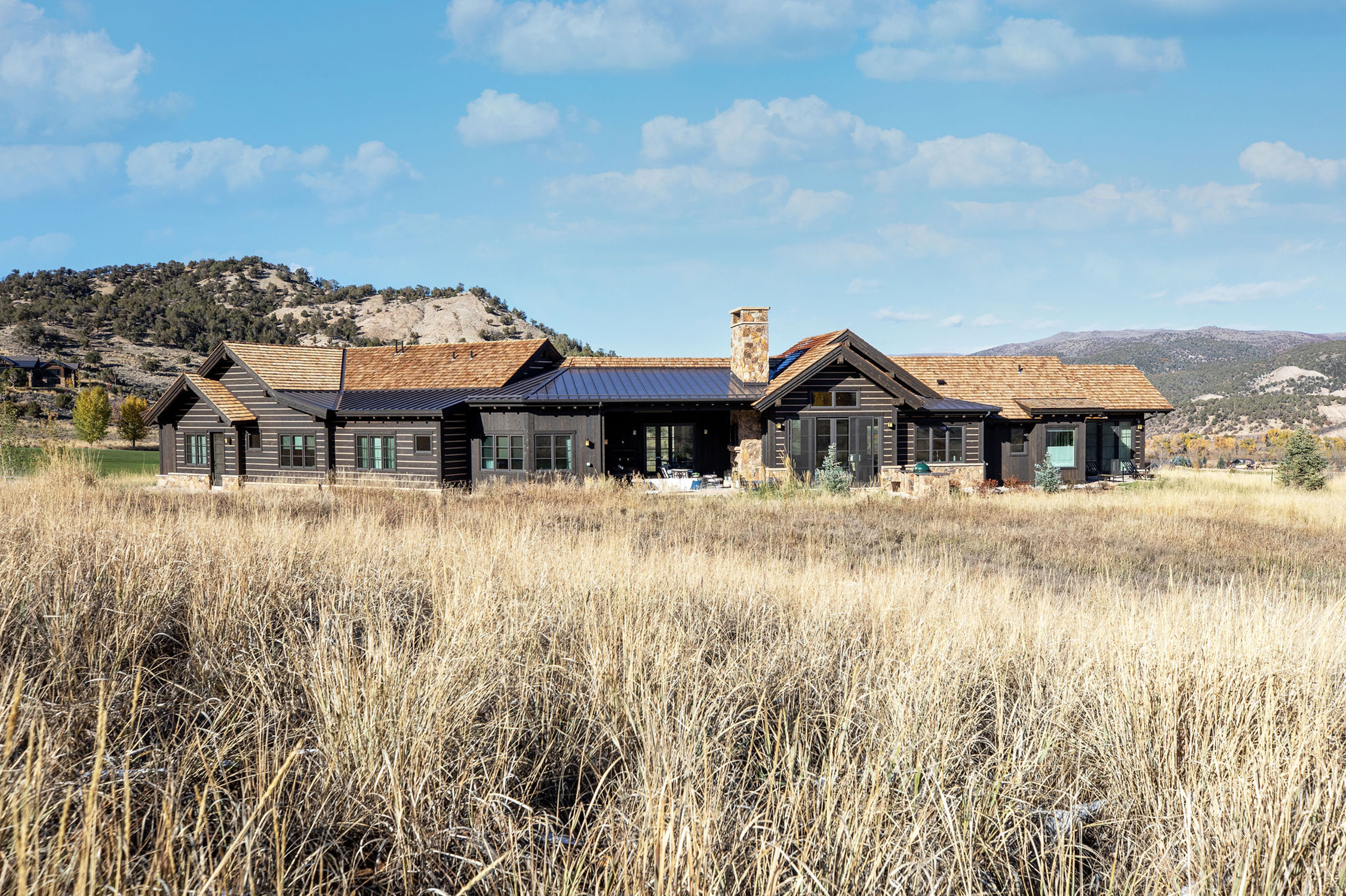 A rustic house surrounded by tall dry grass under a clear blue sky.