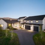 Elegant modern house with large windows and a spacious driveway at dusk.