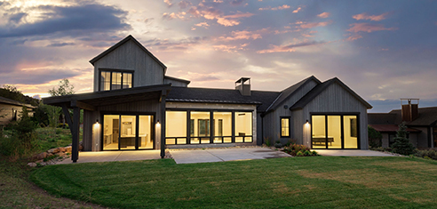 Modern house with large windows under a colorful sunset sky.